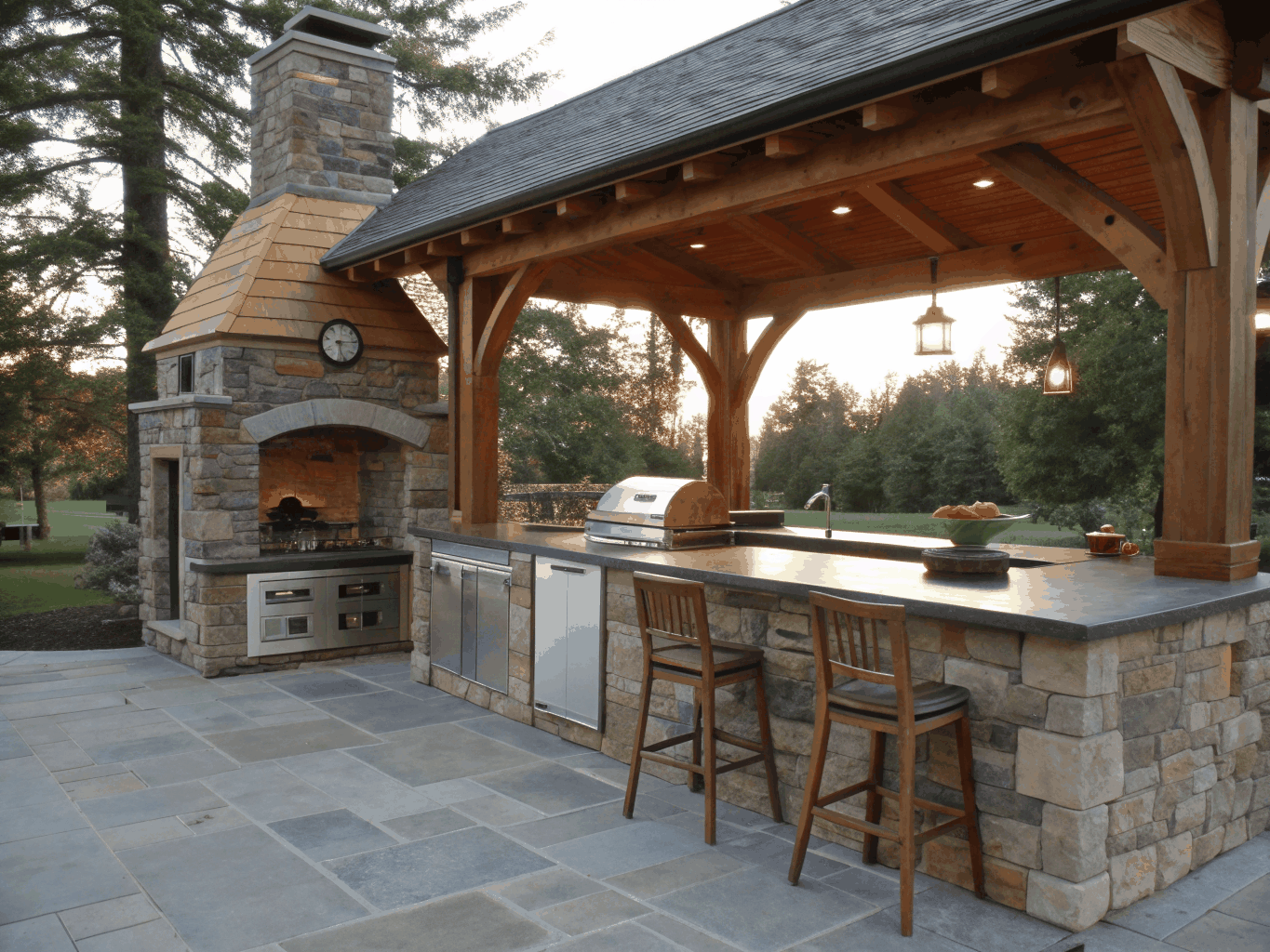 Sunlit timber framed covered patio with stone fireplace and built in outdoor kitchen in Woodstock Georgia